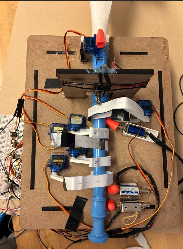 The blue soprano recorder mounted on a laser-cut board, with servo motors, solenoids, and labelled wiring.